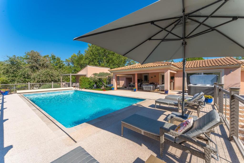 - une piscine avec un parasol et des chaises dans l'établissement T2 Au coeur des chênes 1831 route de Mazaugues, à Saint-Maximin-la-Sainte-Baume