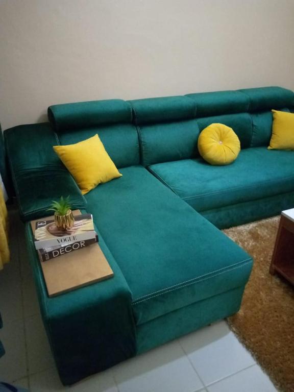 a green couch with yellow pillows and a table at Embu Paradise 1 bedroom AirBNB in Embu