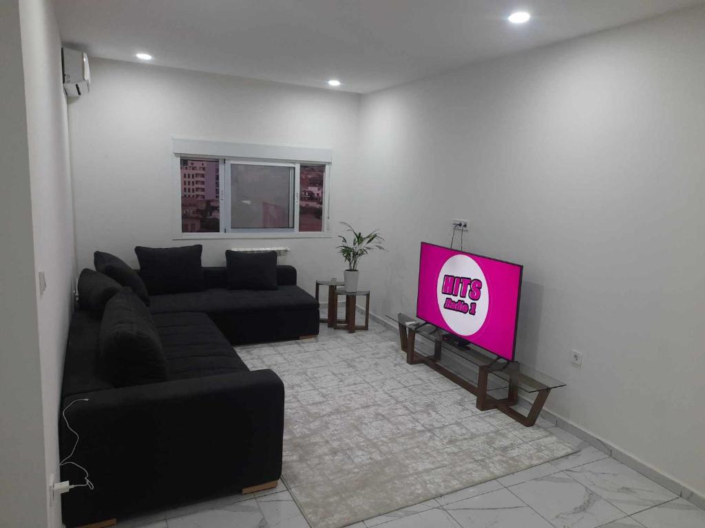 a living room with a black couch and a tv at Résidence amira 5 in Oran