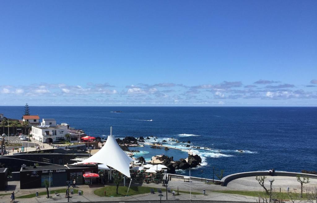 - une vue sur la plage avec une tente blanche et l'océan dans l'établissement Hotel Euro Moniz, à Porto Moniz