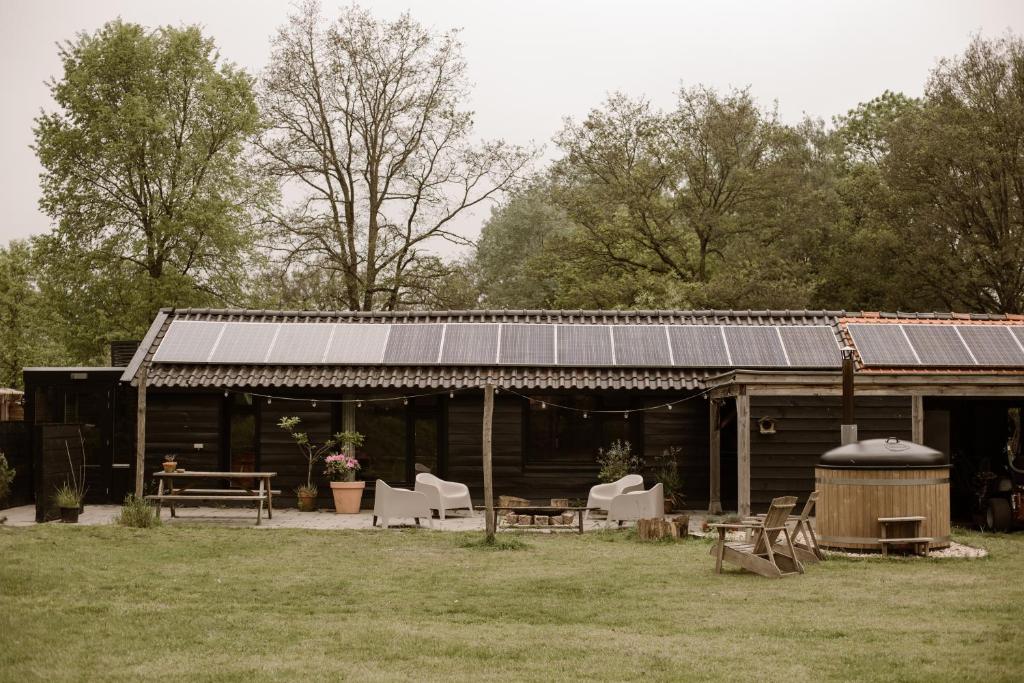 una casa con techo solar con sillas y parrilla en Getaway - Farm House + hottub en Nistelrode