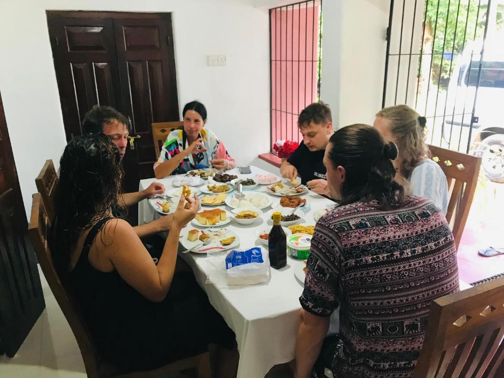 米瑞莎的住宿－太陽泰姬珊瑚度假民宿，一群坐在桌子旁吃食物的人