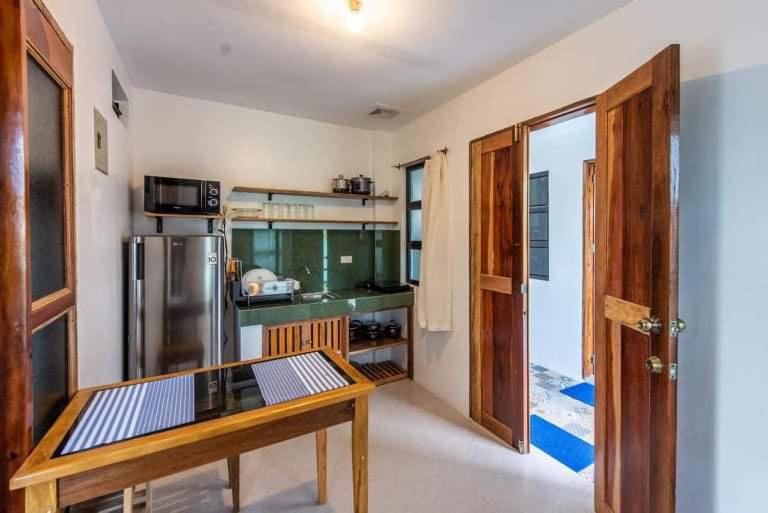 盧納將軍城的住宿－1-BR flat with kitchen private bath hot and cold shower，厨房配有木桌和冰箱。
