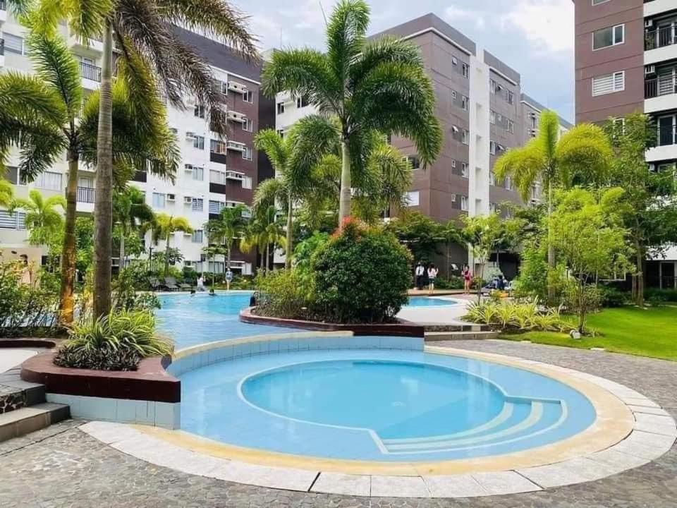a large swimming pool with palm trees and buildings at Avida Tower 1 L21 staycation rm1002 in Iloilo City
