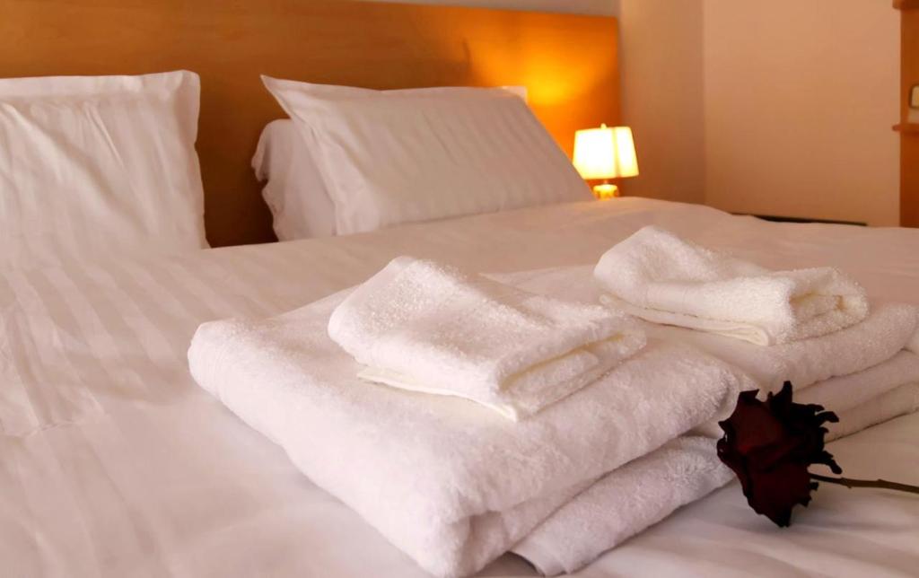 stos ręczników na białym łóżku w obiekcie Beautiful and lovely apartment w Tiranie