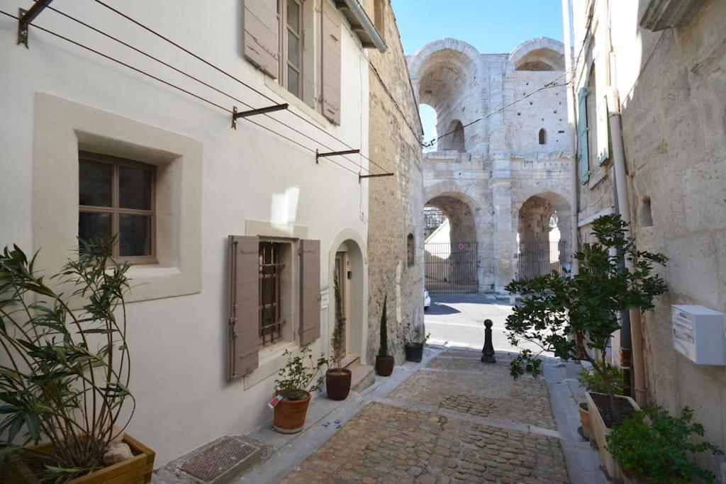 une allée avec des plantes en pot et un bâtiment dans l'établissement Charmante petite maison donnant sur les Arènes, à Arles