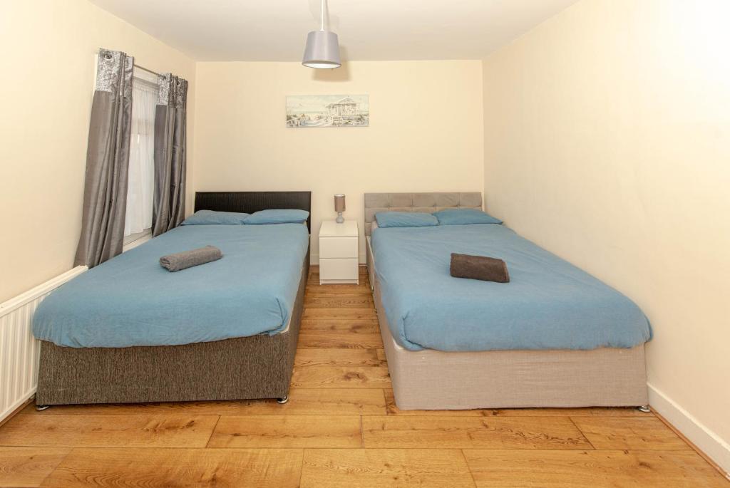 twee bedden in een kleine kamer met houten vloeren bij Cosy 4 bedrooms house near Central London, O2, London city airport and Excel in Plumstead