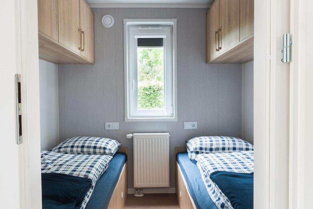 Duas camas num pequeno quarto com uma janela em Chalet Unique em Oldeberkoop