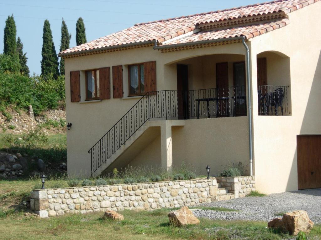 ein Haus mit einem Balkon und einer Steinmauer in der Unterkunft Les Sources Gîte Sauvignon in Chambonas