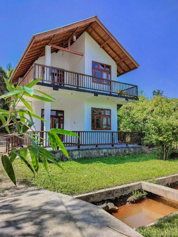 a house with a balcony on top of it at River Relax Villa in Ahangama