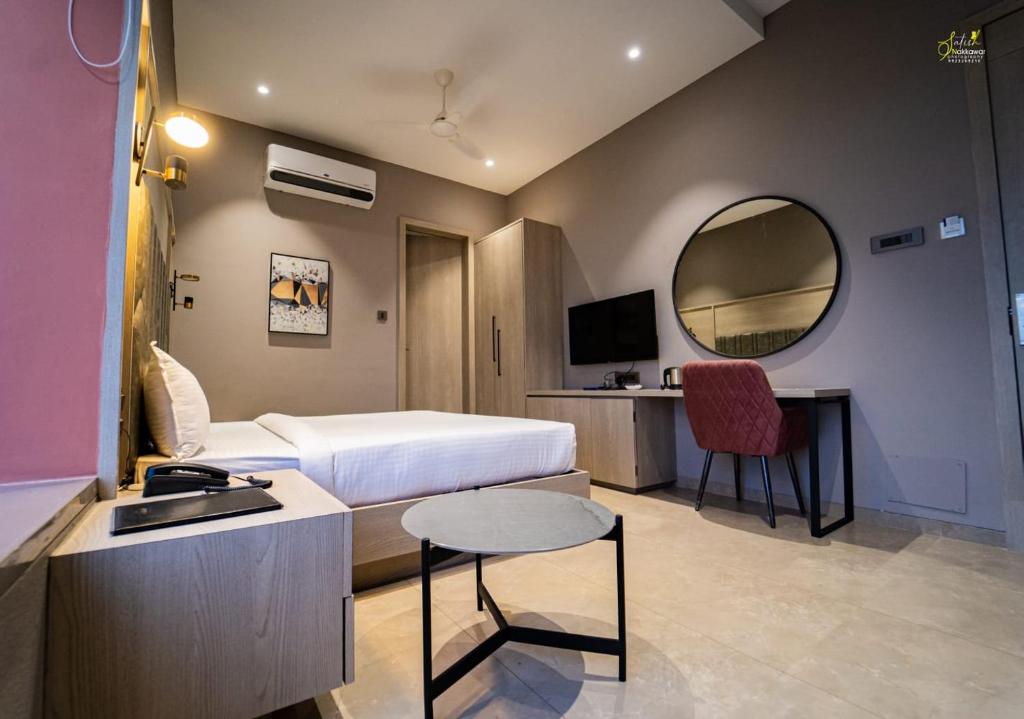 una camera con letto, scrivania e specchio di Hotel Grand Central Park a Nānded