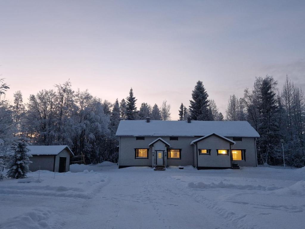 una casa con sus luces encendidas en la nieve en Ainola 2, en Syöte