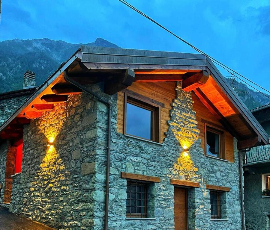 a stone house with lights on the side of it at Lo Stambecco Bianco Chalet in Aosta