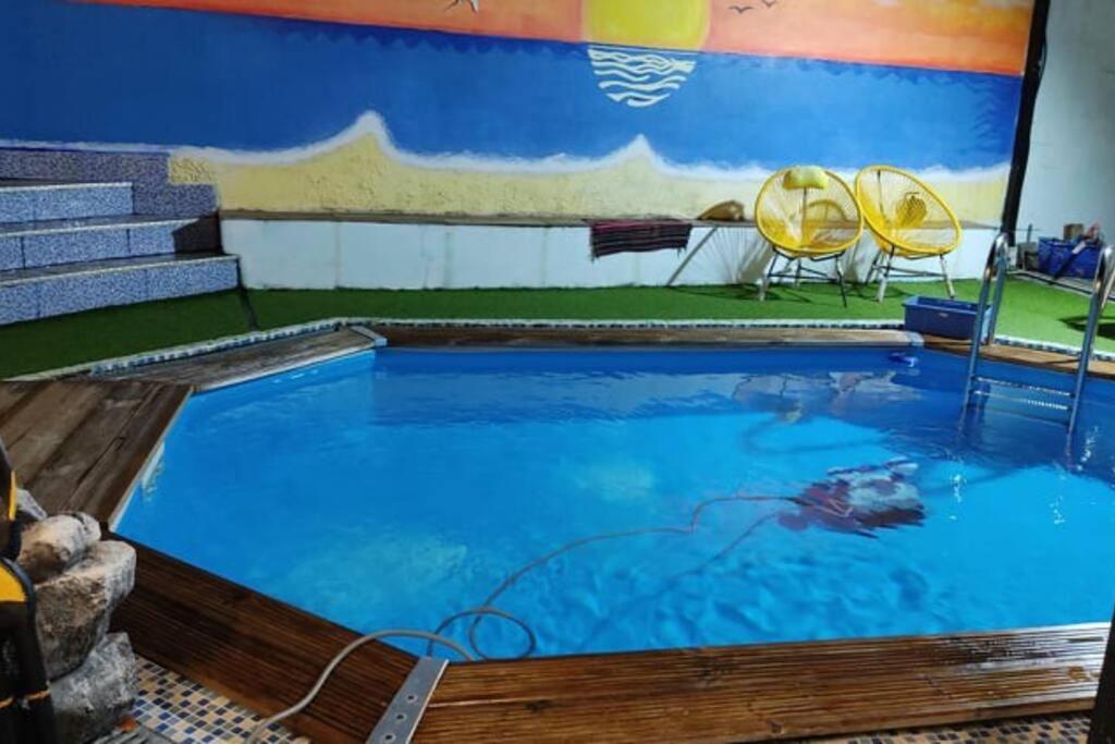 a large swimming pool with two chairs in a room at Agréable Villa équipée avec piscine et barbecue in Sainte-Suzanne