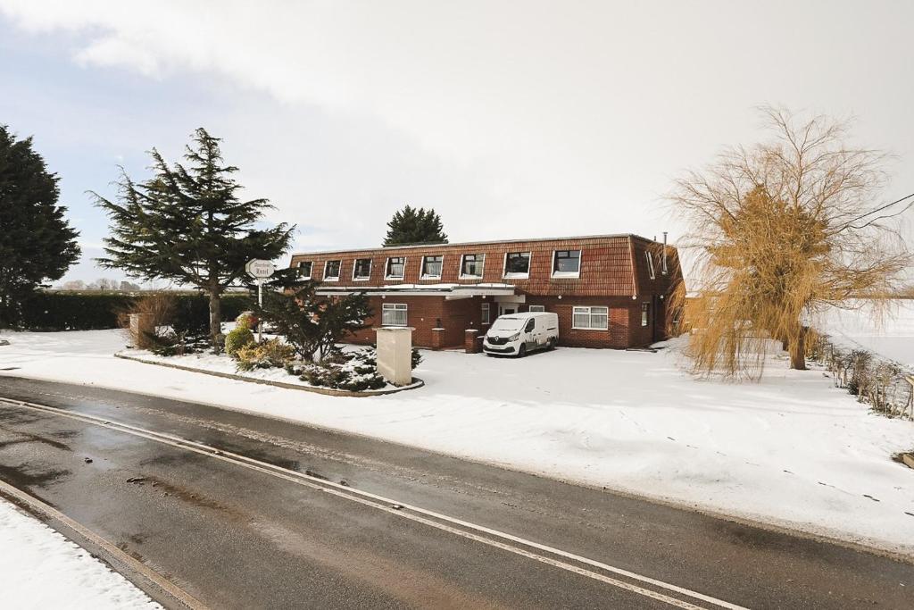 a building with a car parked in front of it in the snow at The Amethyst Hotel - Full House in Immingham