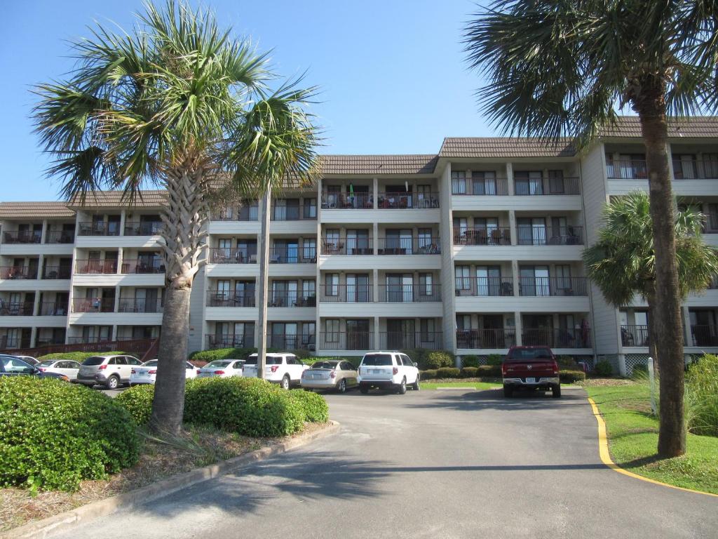 um grande edifício de apartamentos com carros estacionados num parque de estacionamento em Hilton Head Island Beach and Tennis Resort em Hilton Head Island