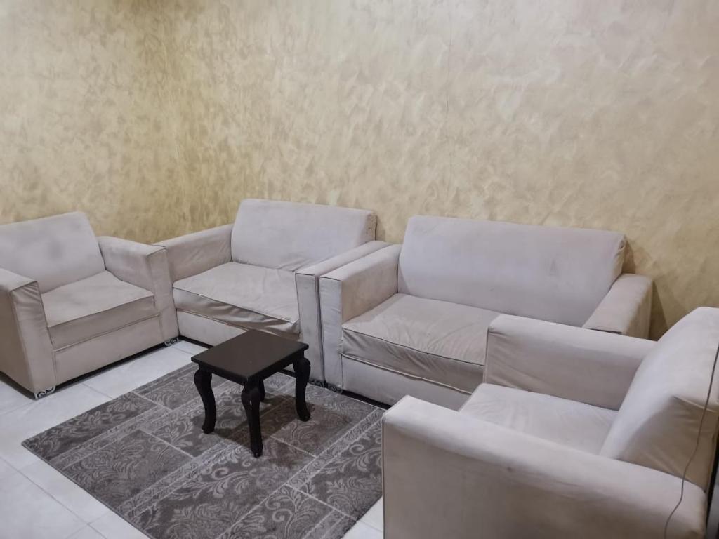 un soggiorno con divani bianchi e tavolino da caffè di اجنحة الازدهار للوحدات السكنية a Rafha