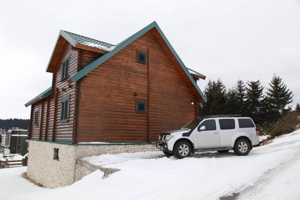 a white suv parked in front of a wooden building at Vila Tea Durmitor in Žabljak