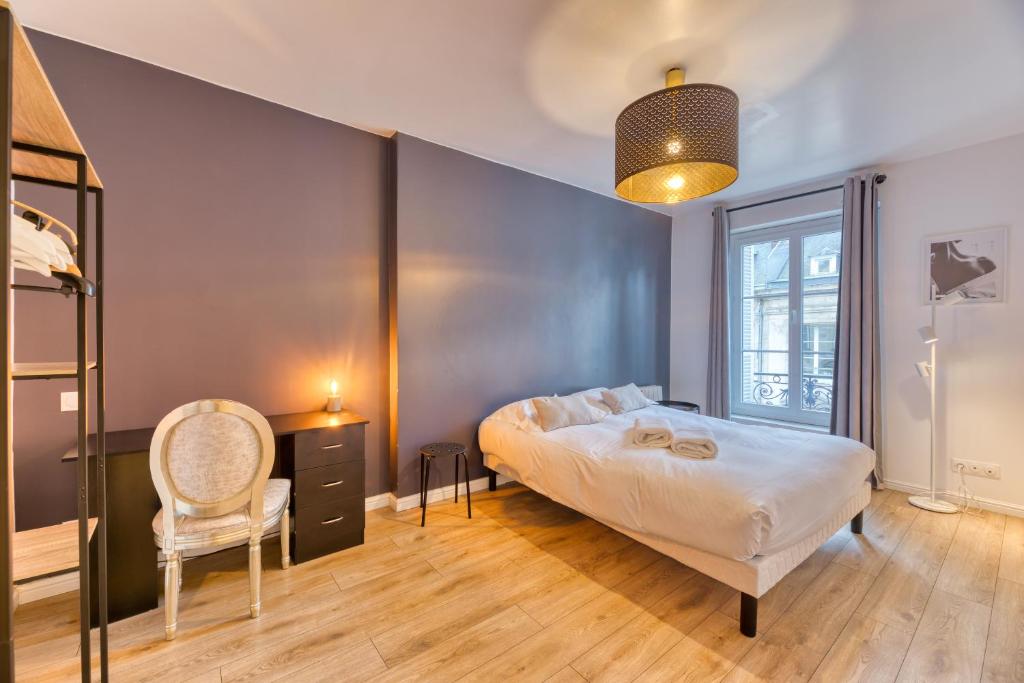 a bedroom with a large bed and a chair at L Axelle magnifique F4 plein centre de Rouen ! in Rouen