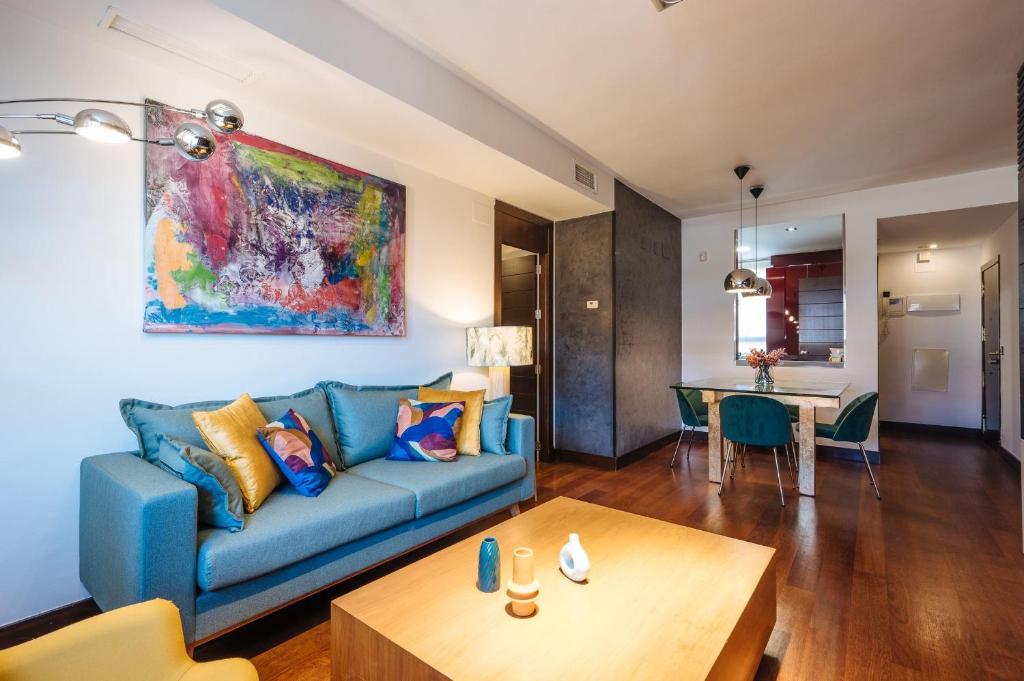 sala de estar con sofá azul y mesa en San Bernardo Home Free Parking en Sevilla