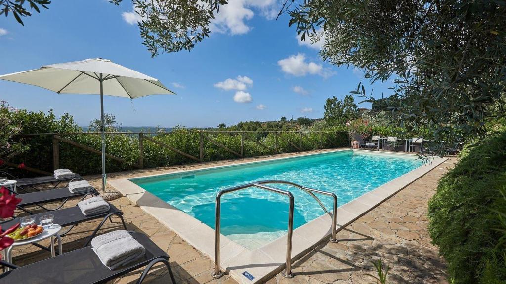 einen Pool mit Sonnenschirm und einigen Stühlen in der Unterkunft Colombaio di Montebenichi in Bucine