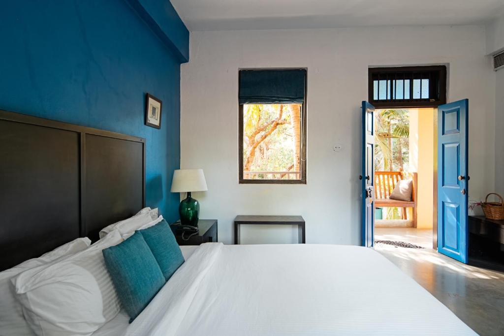 a bedroom with a large white bed with a blue wall at The Secret Cove by Stay ALYF, Baga in Baga