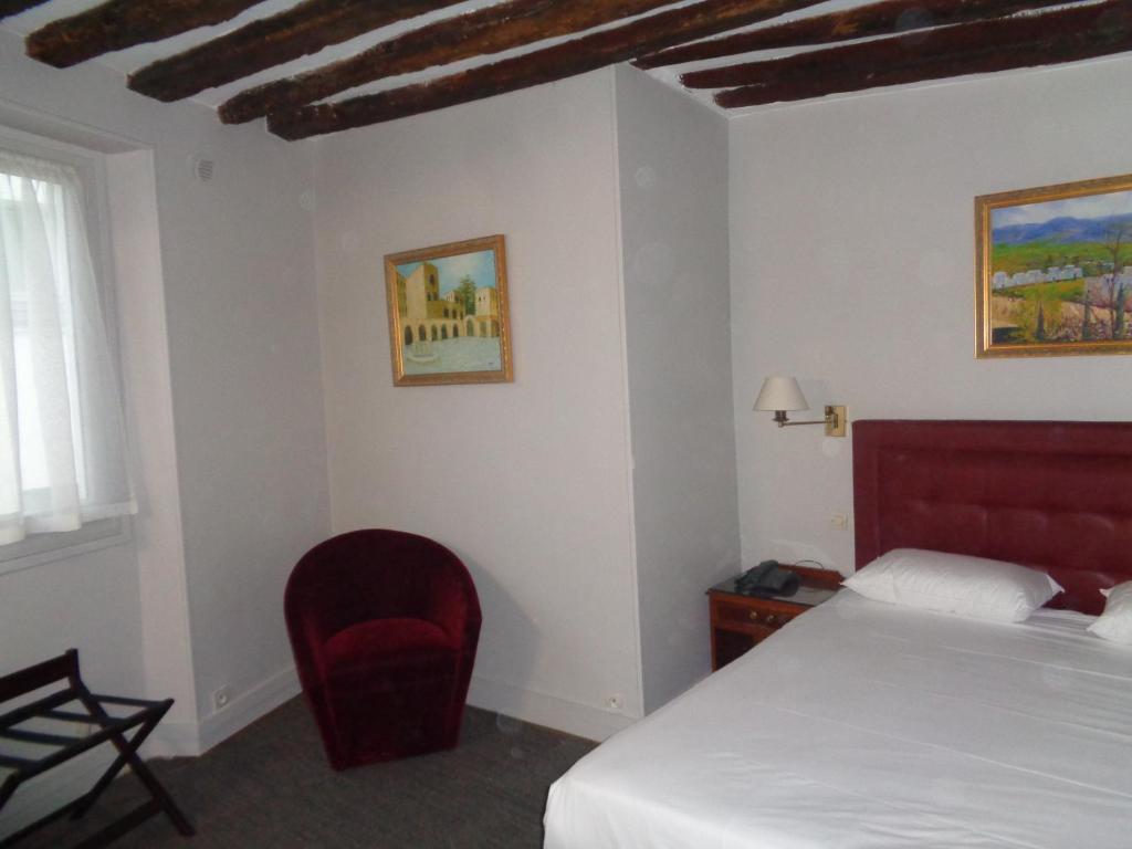 a bedroom with a bed and a red chair at Hôtel les Degrés de Notre Dame in Paris