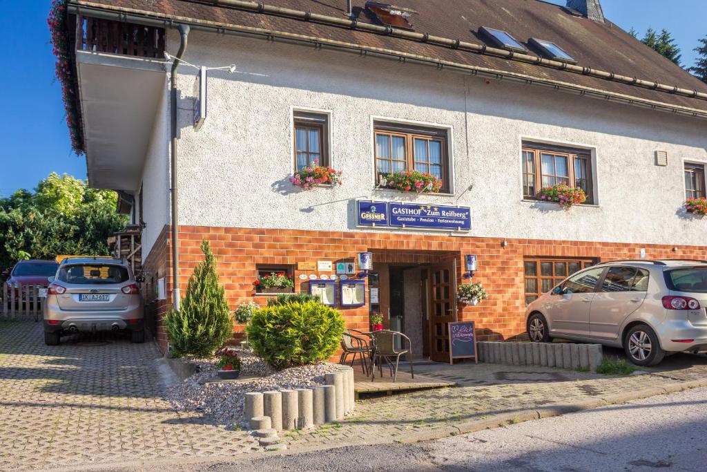 a building with two cars parked in front of it at Gasthof 'Zum Reifberg' in Ilmenau