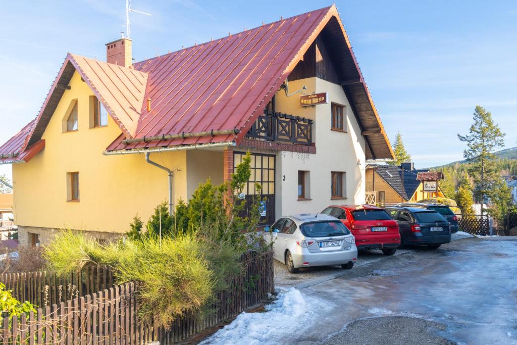 a yellow house with cars parked in a parking lot at Willa Anna Maria in Szklarska Poręba