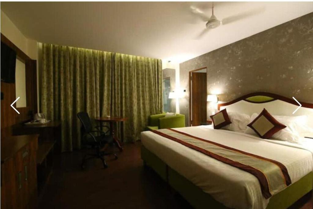 Habitación de hotel con cama y silla en HOTEL BLACK & WHITE en Visakhapatnam