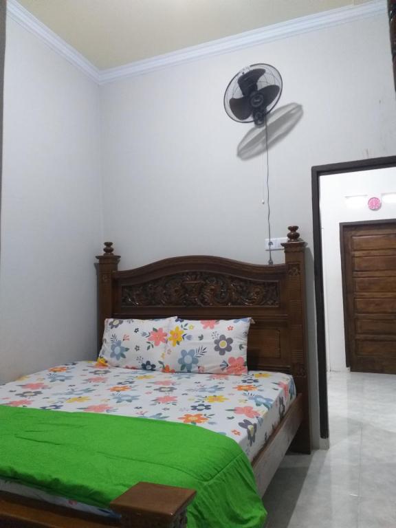 sypialnia z łóżkiem z zielonym kocem i wentylatorem w obiekcie Almahyra Homestay Syariah w mieście Bukittinggi