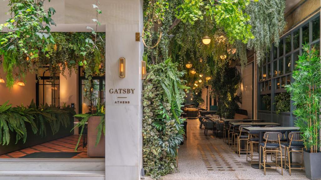 un restaurante con mesas, sillas y plantas en Gatsby Athens en Atenas