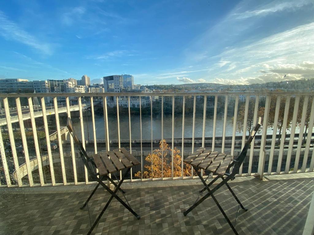 une paire de chaises assises sur un balcon donnant sur l'eau dans l'établissement Appartement sur quai de Seine, à Boulogne-Billancourt