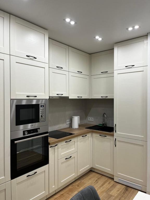 uma cozinha branca com armários e electrodomésticos brancos em VIP Apartmens Avalon em Lviv
