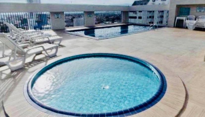 a large swimming pool in a building with chairs at Flat em São Vicente in São Vicente