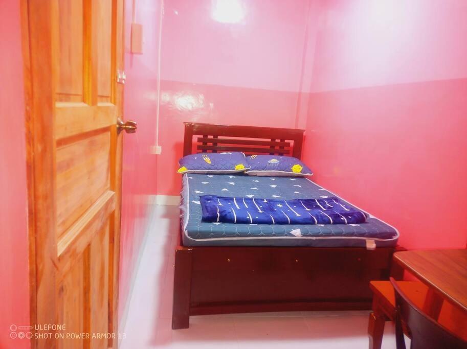 un piccolo letto in una stanza con una parete rossa di Couple Room Pink RODE WAY HOUSE SPACE RENTAL a Pico