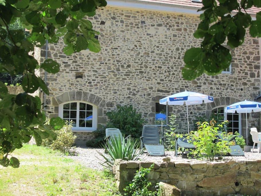 deux chaises et parasols devant un bâtiment dans l'établissement Gîte en bord d'étang et de rivière, à Beynat