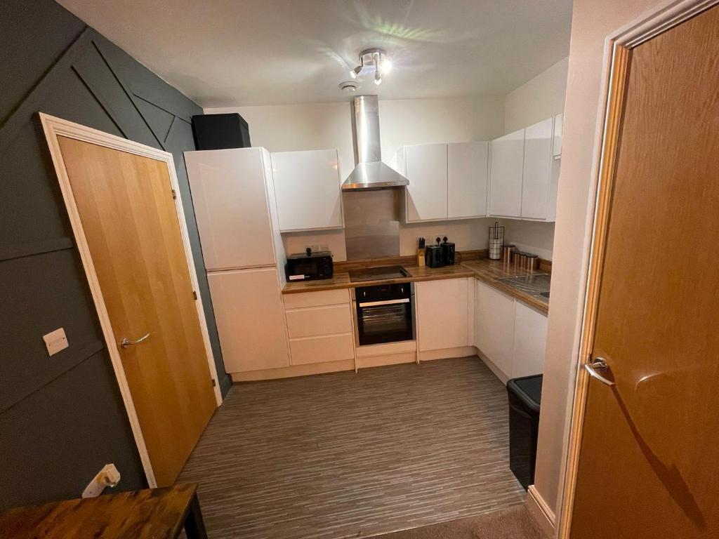 a small kitchen with white cabinets and a stove at Stylish 1-Bed Apartment in Swindon in Swindon