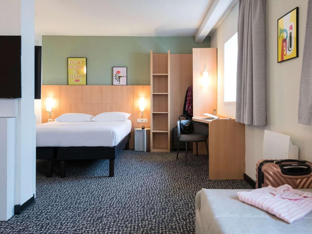 Hotel ibis Rennes Centre Gare Sud في رين: غرفة فندقية بسريرين ومكتب