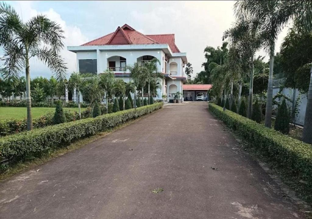 a large white house with a red roof on a road at Chet Residency Namsai in Namsai