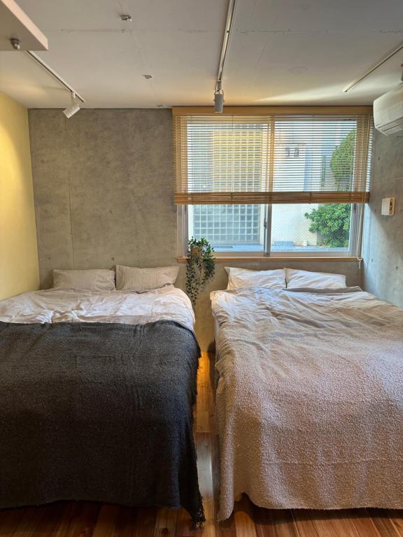 twee bedden in een kamer met een raam bij Style Lab北千住 in Tokyo