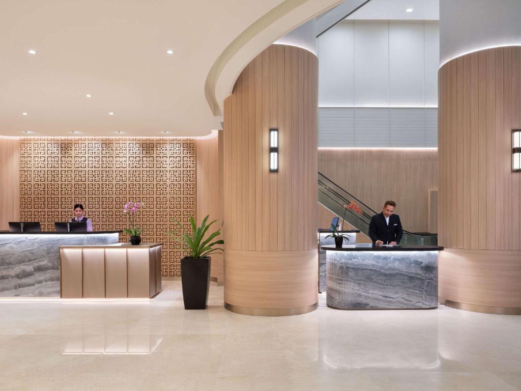 um lobby com duas pessoas sentadas na recepção em Grand Mercure Singapore Roxy em Singapura