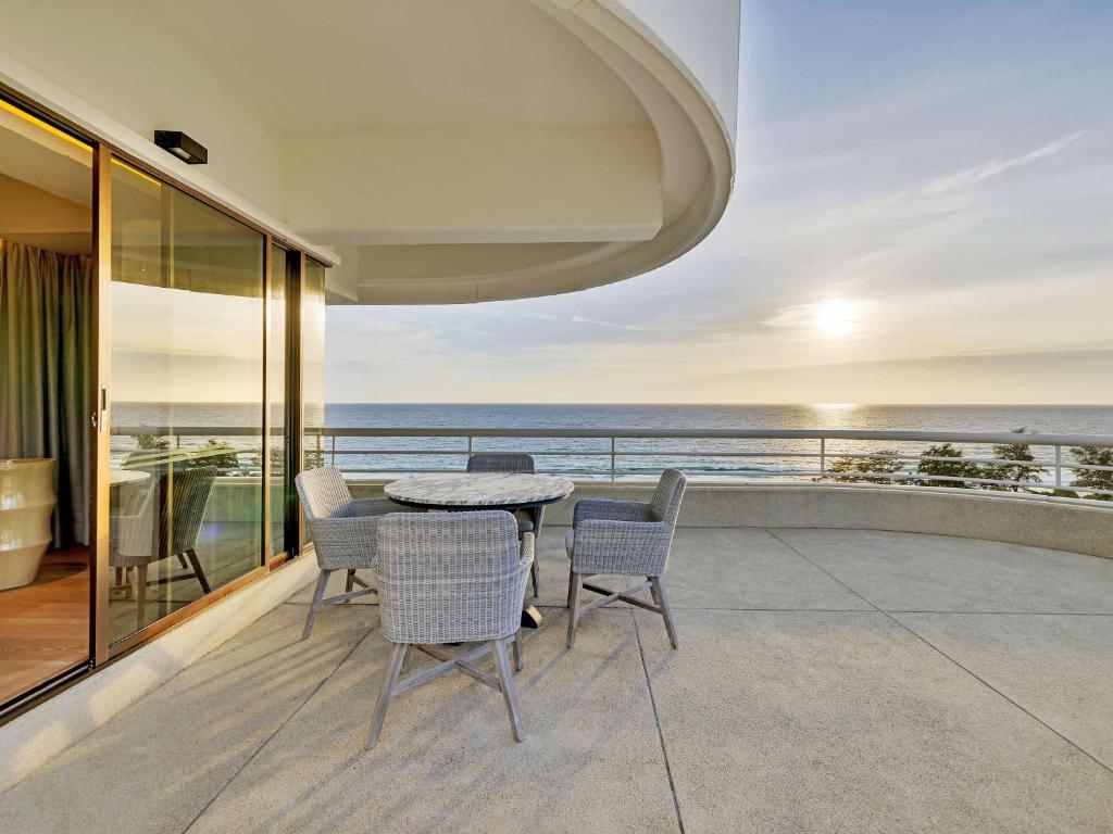 a balcony with a table and chairs and the ocean at Pullman Phuket Karon Beach Resort in Karon Beach