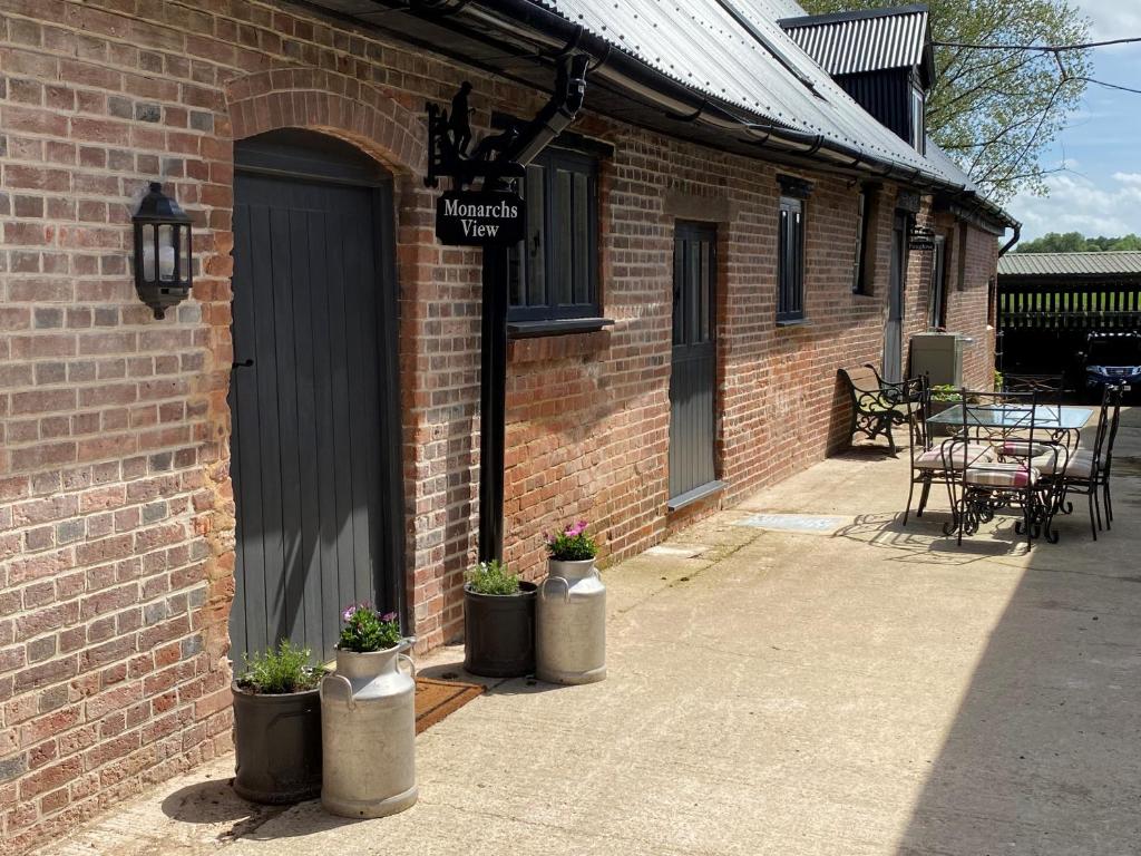 a brick building with three potted plants next to a door at Monarchs View Farmstay in Michelmersh