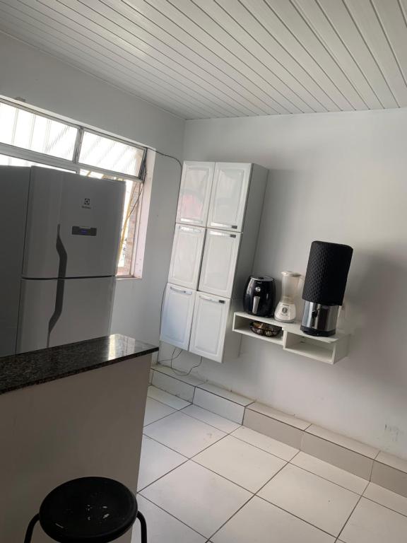 a white kitchen with a refrigerator and a window at Quarto e sala para carnaval in Salvador