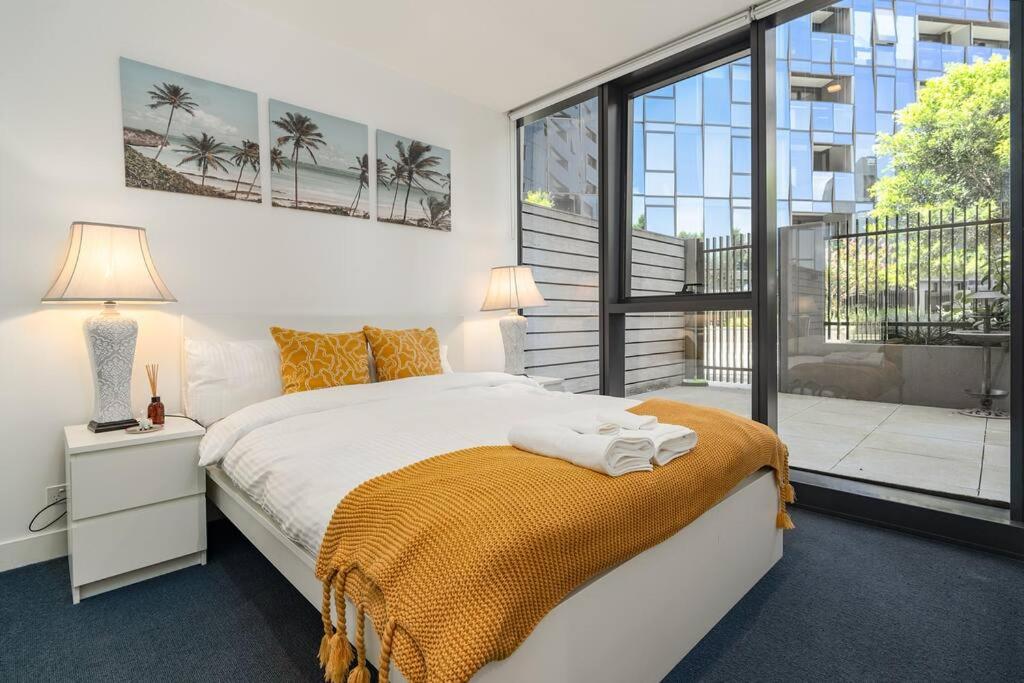 um quarto com uma cama e uma grande janela em 2 BD Luxury apartment at heart of Docklands with 85" flat TV & Free Carpark em Melbourne