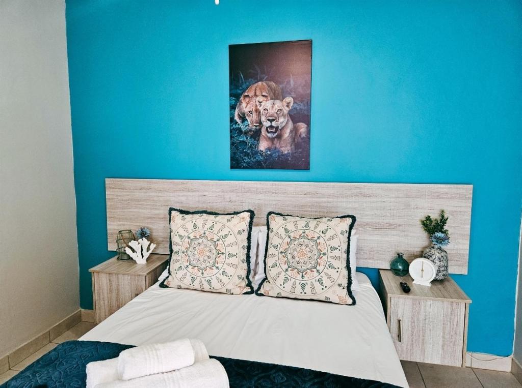 a bedroom with a bed with a blue wall at Sea Breeze Manor - Aqua Unit in East London