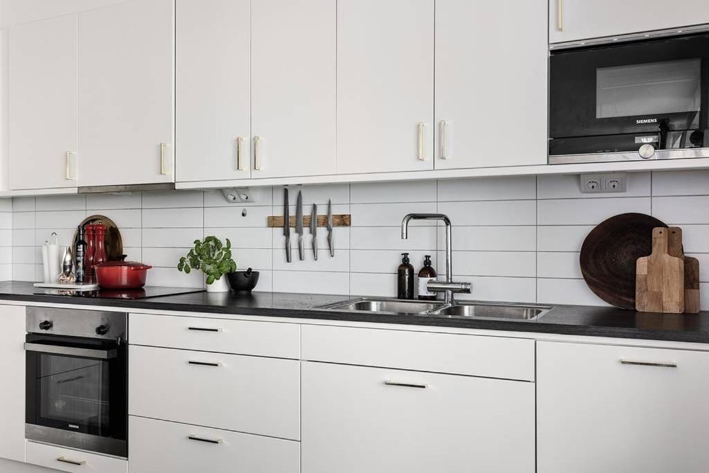 uma cozinha branca com um lavatório e um micro-ondas em Tranquil and Convenience Southern Malmo Apartment em Malmo