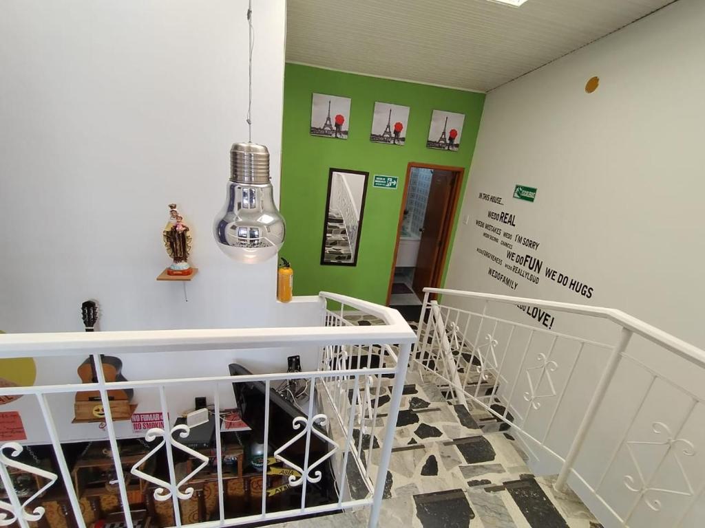 a room with a staircase and green walls and a room with chairs at ZIPA HOSTEL in Zipaquirá