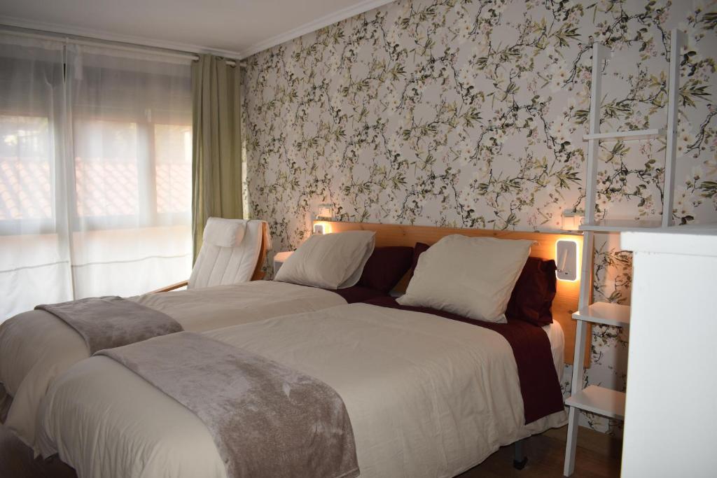um quarto com uma cama e uma parede com papel de parede floral em Casa de Isa VV-2776-AS em Cudillero